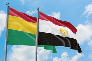 Egypt and Bolivia flags waving in the wind against white cloudy blue sky together. Diplomacy concept, international relations.