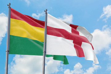 England and Bolivia flags waving in the wind against white cloudy blue sky together. Diplomacy concept, international relations.
