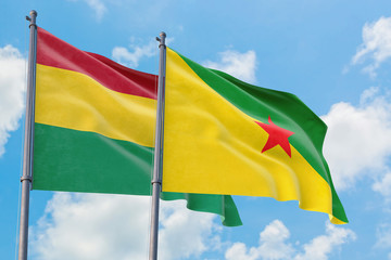 French Guiana and Bolivia flags waving in the wind against white cloudy blue sky together. Diplomacy concept, international relations.