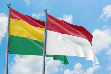 Fototapeta na wymiar Indonesia and Bolivia flags waving in the wind against white cloudy blue sky together. Diplomacy concept, international relations.