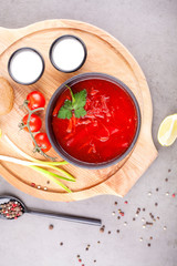 Tomato soup with vegetables, decorated with parsley, in a black plate, on a wooden Board, decorated with tomatoes and onions. Concept soups or healthy food.