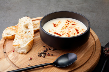 Cheese soup, in a black plate, decorated with spices, served on a wooden board, flat lay. The concept of cheese soup.
