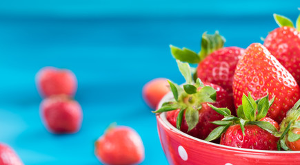 bright printed bowl of fresh strawberries on blue wooden background