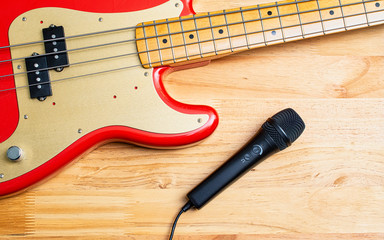 Electric precision bass guitar and microphone resting on wooden desktop in recording studio.