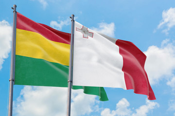 Malta and Bolivia flags waving in the wind against white cloudy blue sky together. Diplomacy concept, international relations.