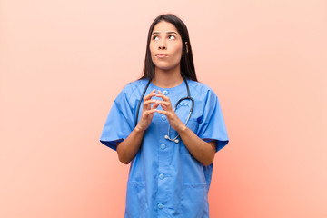 young latin nurse scheming and conspiring, thinking devious tricks and cheats, cunning and...