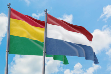 Netherlands and Bolivia flags waving in the wind against white cloudy blue sky together. Diplomacy concept, international relations.