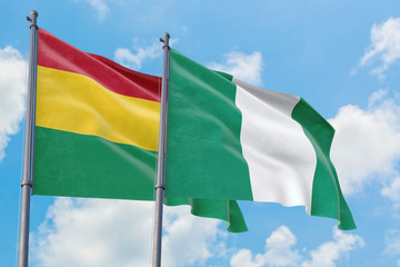 Nigeria and Bolivia flags waving in the wind against white cloudy blue sky together. Diplomacy concept, international relations.