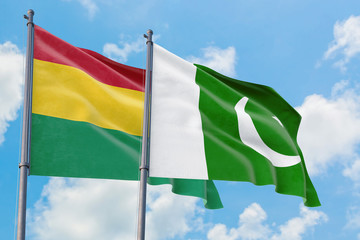 Pakistan and Bolivia flags waving in the wind against white cloudy blue sky together. Diplomacy concept, international relations.