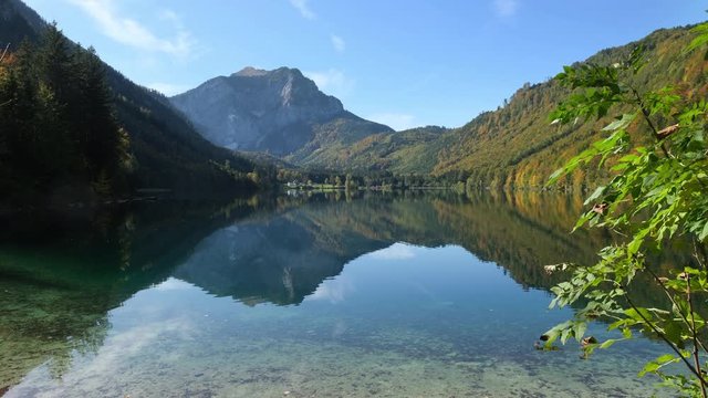 Sunny idyllic colorful autumn alpine video. Peaceful mountain lake with clear transparent water and reflections. Langbathseen lake, Upper Austria.