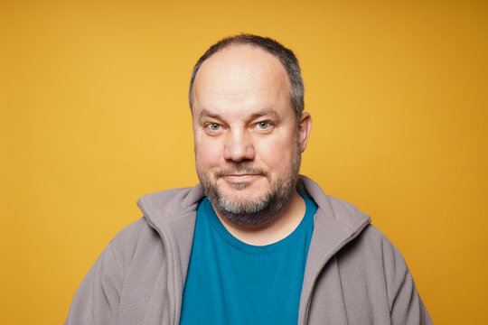 casual chubby confident mature man against yellow background with copy space