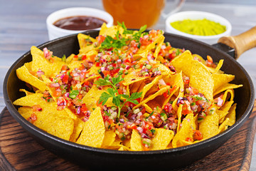 Mexican nachos with cheese. Corn chips with guacamole, salsa and tomato ketchup.