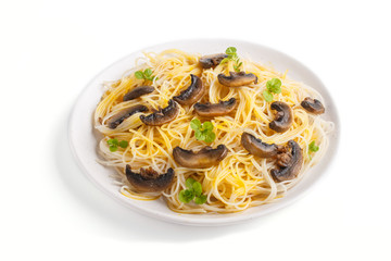 Rice noodles with champignons mushrooms, egg sauce and oregano on white ceramic plate isolated on white background. side view.