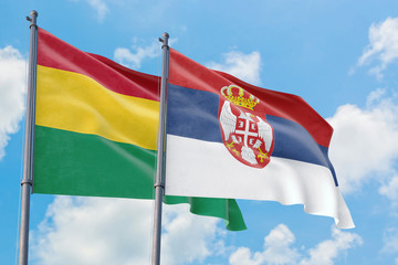 Serbia and Bolivia flags waving in the wind against white cloudy blue sky together. Diplomacy concept, international relations.