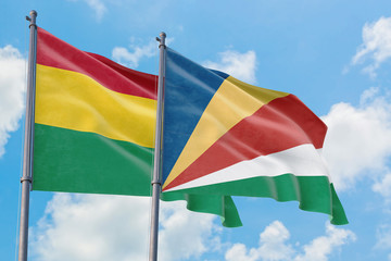 Seychelles and Bolivia flags waving in the wind against white cloudy blue sky together. Diplomacy concept, international relations.