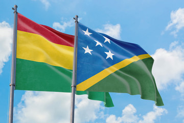 Solomon Islands and Bolivia flags waving in the wind against white cloudy blue sky together. Diplomacy concept, international relations.