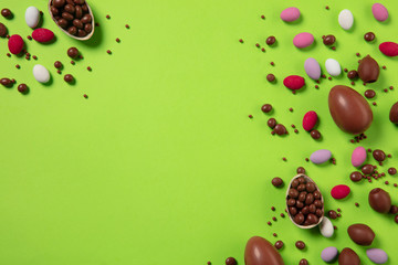 Egg hunt is coming. Easter traditions, chocolate eggs, candies on green background, top view, copyspace for your ad or greetings. Concept of holidays, spring, celebrating, food and sweets, family time