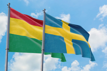 Sweden and Bolivia flags waving in the wind against white cloudy blue sky together. Diplomacy concept, international relations.