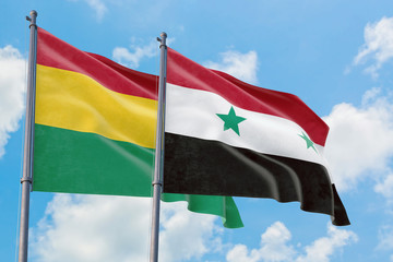 Syria and Bolivia flags waving in the wind against white cloudy blue sky together. Diplomacy...