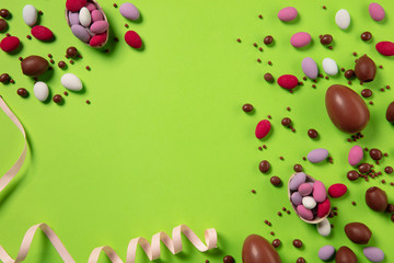 Egg hunt is coming. Easter traditions, chocolate eggs, candies on green background, top view, copyspace for your ad or greetings. Concept of holidays, spring, celebrating, food and sweets, family time