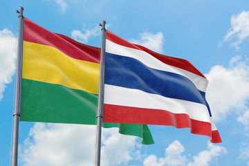 Thailand and Bolivia flags waving in the wind against white cloudy blue sky together. Diplomacy concept, international relations.