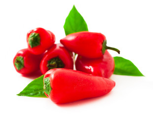 Sweet red peppers with green leaves isolated on a white background.