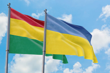Ukraine and Bolivia flags waving in the wind against white cloudy blue sky together. Diplomacy concept, international relations.