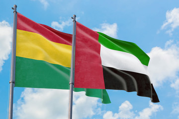 United Arab Emirates and Bolivia flags waving in the wind against white cloudy blue sky together. Diplomacy concept, international relations.