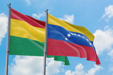 Venezuela and Bolivia flags waving in the wind against white cloudy blue sky together. Diplomacy concept, international relations.