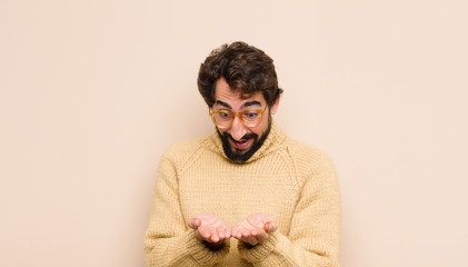 young cool man smiling happily with friendly, confident, positive look, offering and showing an...