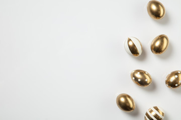 Egg hunt is coming. Easter traditions, golden colored eggs on white background, top view, copyspace for your ad or greetings. Concept of holidays, spring, celebrating, food and sweets, family time.
