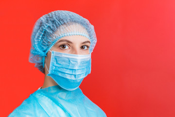 Portrait of a woman wearing medical uniform and mask at red background. Coronavirus concept....