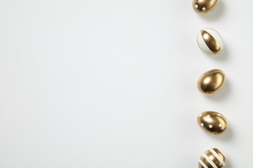 Egg hunt is coming. Easter traditions, golden colored eggs on white background, top view, copyspace for your ad or greetings. Concept of holidays, spring, celebrating, food and sweets, family time.