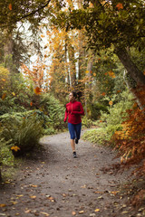 Fototapeta na wymiar Young woman running on gravel path in autumn the park. Female athlete traning outdoor.
