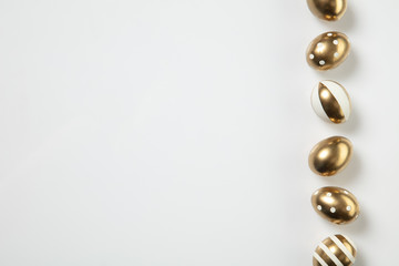 Egg hunt is coming. Easter traditions, golden colored eggs on white background, top view, copyspace for your ad or greetings. Concept of holidays, spring, celebrating, food and sweets, family time.