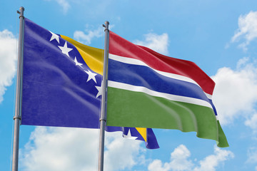 Gambia and Bosnia Herzegovina flags waving in the wind against white cloudy blue sky together. Diplomacy concept, international relations.