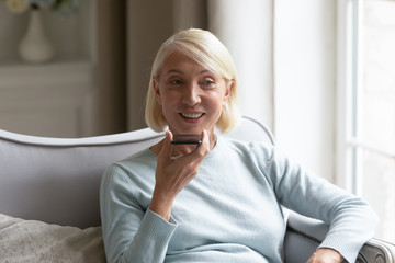Middle-aged woman talk on cellphone using loudspeaker