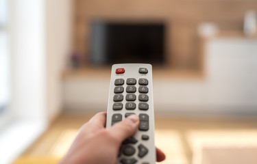 Watching television in the living room. Holding remote control. Free time. Relaxing. 