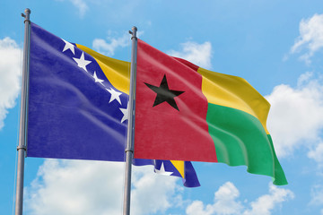 Guinea Bissau and Bosnia Herzegovina flags waving in the wind against white cloudy blue sky together. Diplomacy concept, international relations.