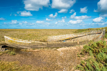 Rustic old boat left to decay on Salt Marshes between Blakeney and Cley next the sea coastal villages on North Norfolk Coast, East of England, UK.