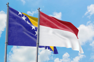 Indonesia and Bosnia Herzegovina flags waving in the wind against white cloudy blue sky together. Diplomacy concept, international relations.