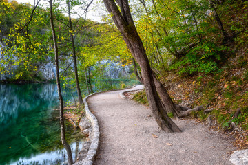 Amazing autumn landscape with tourist route in a forest along the lake with crystal clear water, outdoor travel background, Plitvice lakes (Plitvicka jezera) national park, Croatia