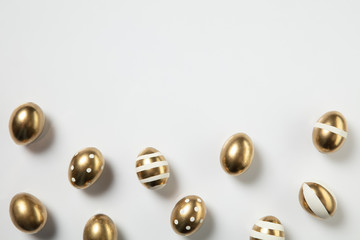Egg hunt is coming. Easter traditions, golden colored eggs on white background, top view, copyspace for your ad or greetings. Concept of holidays, spring, celebrating, food and sweets, family time.