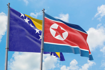 North Korea and Bosnia Herzegovina flags waving in the wind against white cloudy blue sky together. Diplomacy concept, international relations.