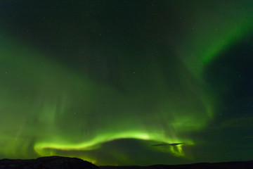Aurora borealis over the hills. At night in the sky in the north.