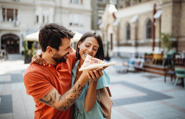 Happy couple eating pizza while traveling on vacation