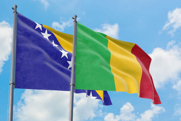 Mali and Bosnia Herzegovina flags waving in the wind against white cloudy blue sky together. Diplomacy concept, international relations.