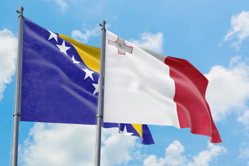 Malta and Bosnia Herzegovina flags waving in the wind against white cloudy blue sky together. Diplomacy concept, international relations.