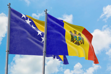 Moldova and Bosnia Herzegovina flags waving in the wind against white cloudy blue sky together. Diplomacy concept, international relations.