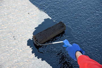 Worker applies bitumen mastic on the foundation. Waterproofing